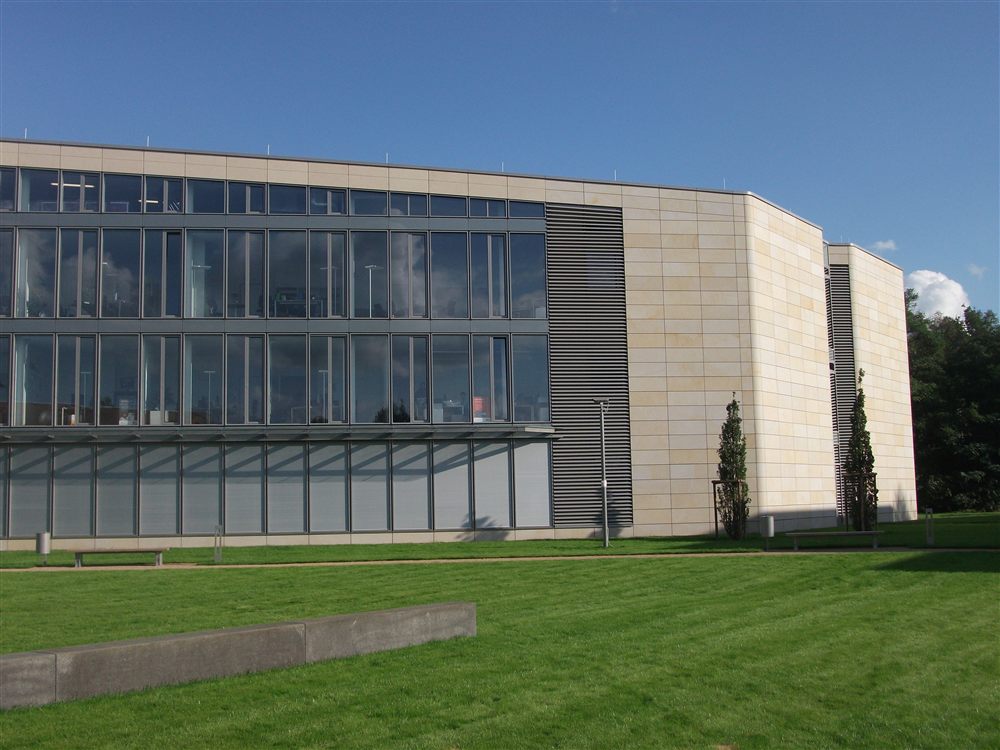 Modernes Gebäude mit großflächiger Fassadenverkleidung aus Sandstein und Glas