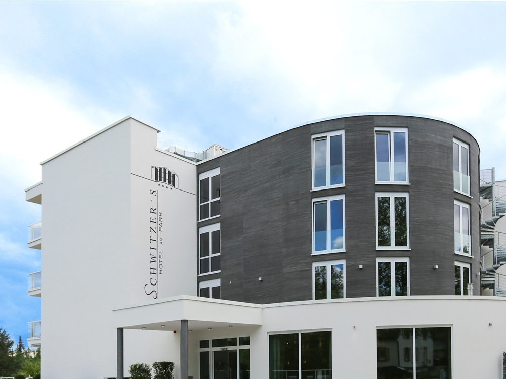 Hotel mit rundem Gebäudeteil und Fassadenverkleidung in dunklem Stein