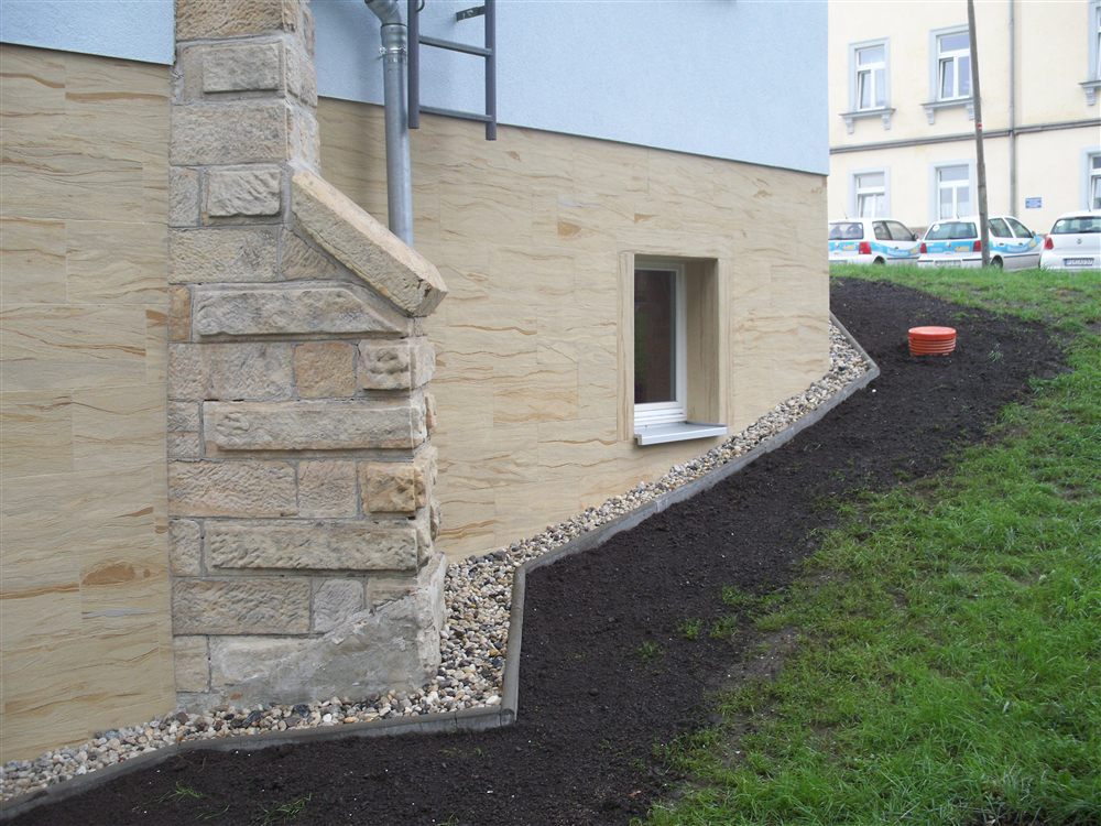 Haussockel mit Sandsteinverkleidung neben altem Sandsteinpfeiler