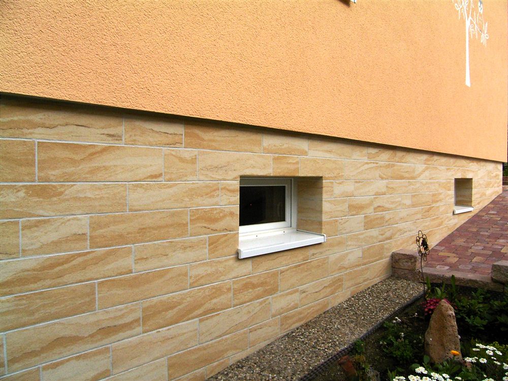 Sockel eines Wohnhauses mit Sandsteinverkleidung und Fenster
